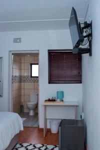 ein Schlafzimmer mit einem Bett und einem TV an der Wand in der Unterkunft Rio Lodge in Butterworth