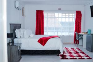 Schlafzimmer mit einem Bett mit roten Vorhängen und einem Fenster in der Unterkunft Rio Lodge in Butterworth