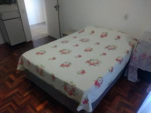 Una cama con una manta blanca con flores. en Quarto em Apto Compartilhado BEIRA MAR, en Maceió