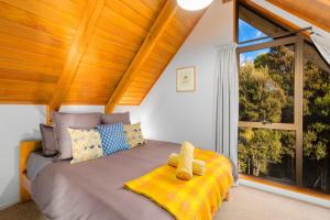 a bedroom with a bed with a teddy bear on a yellow blanket at Totara Lodge - Unwind, Relax & Enjoy - Mt Lyford in Mt Lyford