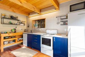 una cucina con armadi blu e frigorifero bianco di Totara Lodge - Unwind, Relax & Enjoy - Mt Lyford a Mt Lyford