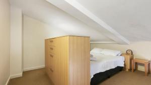 a bedroom with a bed and a wooden cabinet at Chalet Hotham 17 in Mount Hotham