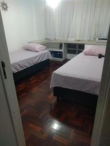 1 dormitorio con 2 camas y suelo de madera en Quarto em Apto Compartilhado BEIRA MAR, en Maceió