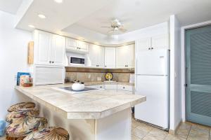 a kitchen with white cabinets and a white refrigerator at Condo On the Ocean, Lagoon and Garden - Hale Kona Kai 411 by Casago Kona in Kailua-Kona +15 photos