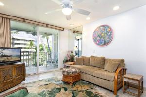 a living room with a couch and a tv at Condo On the Ocean, Lagoon and Garden - Hale Kona Kai 411 by Casago Kona in Kailua-Kona