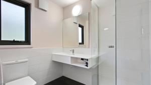 a white bathroom with a sink and a toilet at Snowtel 4 in Mount Hotham +9 photos