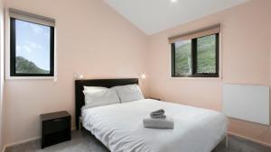 a bedroom with a white bed with two windows at Snowtel 4 in Mount Hotham