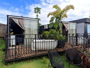 una terraza cubierta con 2 sillas y una casa en Tiny House Paraiso Minicasas Com Hidromassagem en Pouso Alegre