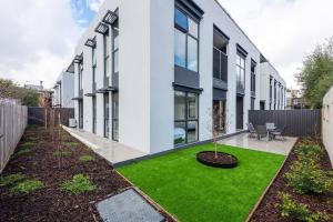 un jardin avec de l'herbe verte en face d'un bâtiment dans l'établissement Modern 3BR Getaway next to Chadstone, à Oakleigh