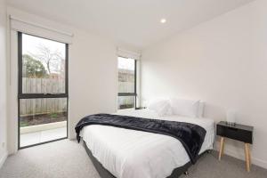 Un dormitorio blanco con una cama grande y una ventana en Modern 3BR Getaway next to Chadstone, en Oakleigh