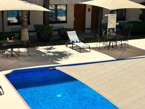 una piscina con sillas, mesas y sombrillas en Hotel Colonial Ciudad Juarez en Ciudad Juárez