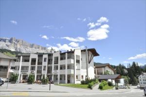 un gran edificio blanco con una montaña en el fondo en Residence Nagler - BelaVal Apartments, en Badia