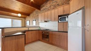 a kitchen with wooden cabinets and a white refrigerator at Lawlers 34 in Mount Hotham