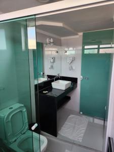 La salle de bains est pourvue de toilettes vertes et d'un lavabo. dans l'établissement Araras Apart Service Caldas Novas, à Caldas Novas