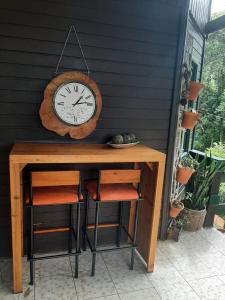 a clock on a wall next to a table with two stools at Casa de campo em Monte Verde , linda vista para montanhas in Monte Verde