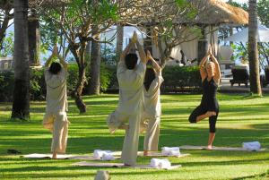 a group of people doing yoga in the grass at Spa Village Resort Tembok Bali - Small Luxury Hotels of the World in Tejakula