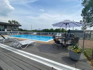 a deck with a table and an umbrella next to a pool at Rockwood Resort Motel in Lake Ozark
