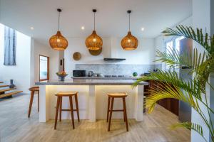 een keuken met hanglampen en een aanrecht met krukken bij Villa Santosa Heights in Kuta Lombok