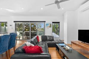 a living room with a black leather couch and a tv at Sunset Days Family Holiday House 200m to Shops in Ocean Grove