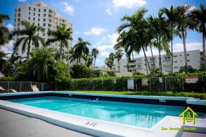 a swimming pool with palm trees and a building at BH Club by Zen Vacation Rentals 2BR 1BA in Miami Beach