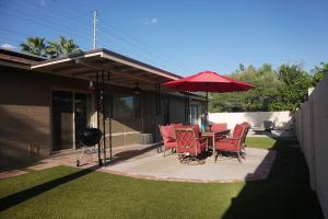 a patio with a table and chairs and an umbrella at 3bdr Remodeled Scottsdale Desert Pool Oasis and Entertainment in Phoenix