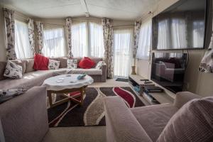 費利克斯托的住宿－6 Berth Caravan With Decking And Wifi At Suffolk Sands Holiday Park Ref 45082c，带沙发和电视的客厅