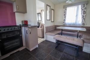 a small kitchen with a table and a stove at 6 Berth Caravan With Decking And Wifi At Suffolk Sands Holiday Park Ref 45082c in Felixstowe