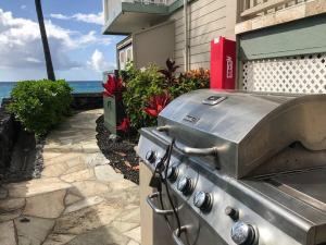 a grill on a patio with the ocean in the background at Beautifully Renovated Oceanfront Condo w/ breathe taking Views! - Hale Kona Kai 302 in Kailua-Kona