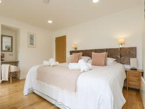 1 dormitorio con 1 cama grande con sábanas blancas y almohadas rosas en Birch, en Truro