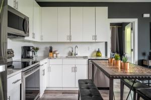 a white kitchen with white cabinets and a table at Downtown New-Built Roof-top balcony City View 525Pkwy419 in Atlanta