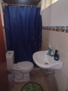 y baño con aseo, lavabo y cortina de ducha azul. en hostal Sueño Paraiso- Observatorio astronómico, en Popayán