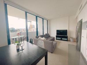 a living room with a couch and a television at Cosy and Stylish 1 BD Serviced Apt at SouthBank in Brisbane