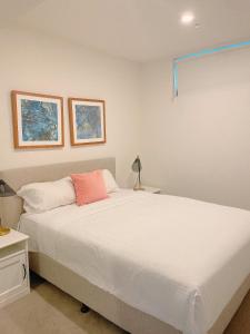 a bedroom with a large white bed with a pink pillow at Cosy and Stylish 1 BD Serviced Apt at SouthBank in Brisbane
