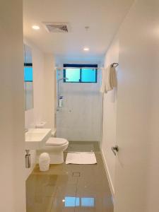 a white bathroom with a toilet and a sink at Cosy and Stylish 1 BD Serviced Apt at SouthBank in Brisbane