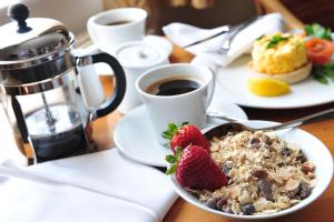 a table with a bowl of cereal and strawberries and a cup of coffee at The White Lion Hotel in Aldeburgh