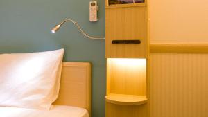 a bedroom with a bed and a lamp on a wall at Toyoko Inn Osaka Namba in Osaka