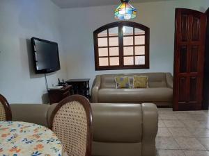 ein Wohnzimmer mit einem Sofa und einem TV in der Unterkunft Casa de Praia Ibicuí in Mangaratiba