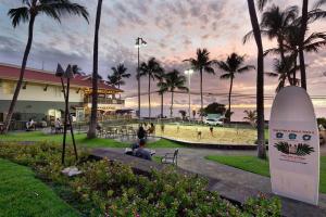 カイルア・コナにあるOceanfront Condo with Lanai that Almost Hangs Over Ocean - Hale Kona Kai 304 by Casago Konaの公園のサーフボードの横に腰掛けた男