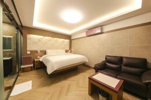 ein Hotelzimmer mit einem Bett und einem Sofa in der Unterkunft Sugar Hotel in Gyeongju