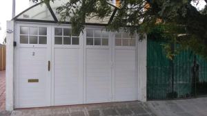 a garage with two white doors and a fence at Silvia 1 in Olavarría