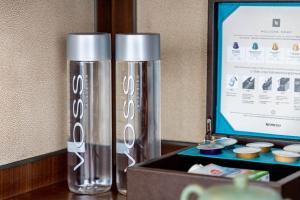 two silver water bottles sitting next to a computer monitor at Raffles Shenzhen, Enjoy the daily happy hour in Long Bar, complimentary mini bar and welcome amenities in Shenzhen