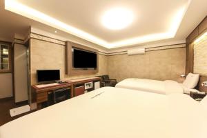 um quarto com uma cama e uma televisão de ecrã plano em Sugar Hotel em Gyeongju