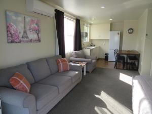 a living room with a couch and a kitchen at Commodore Court Motel in Blenheim