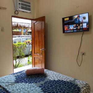 a bedroom with a bed with a television on the wall at Hostal Tierra y Mar in Montañita