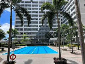 un grand immeuble avec piscine et palmiers dans l'établissement 1BR @ Grace Taguig near NAIA & BGC, à Manille
