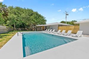 una piscina con sillas y una casa en Paradise Palms- Tropic Suite- Pool - Steps to Ocean - 10 min to Downtown en St. Augustine
