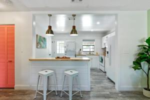 a kitchen with white walls and a counter and stools at Paradise Palms- Tropic Suite- Pool - Steps to Ocean - 10 min to Downtown in Saint Augustine