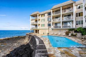 a building with a swimming pool next to the ocean at Dreamy True Oceanfront Condo - Hale Kona Kai 307 by Casago Kona in Kailua-Kona