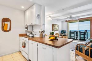 a kitchen with white cabinets and a table with fruit on the counter at Dreamy True Oceanfront Condo - Hale Kona Kai 307 by Casago Kona in Kailua-Kona