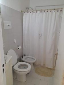 a white bathroom with a toilet and a shower at Depto Rawson Home in Rawson